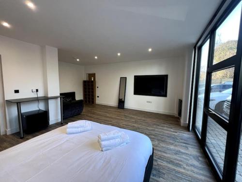 a bedroom with a white bed and a flat screen tv at Modern Studio Apartment Near Glenfield Hospital in Glenfield