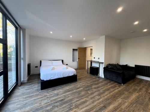 a large bedroom with a bed and a couch at Modern Studio Apartment Near Glenfield Hospital in Glenfield