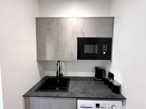 cocina con fregadero y microondas en Hospital View Apartment en Glenfield