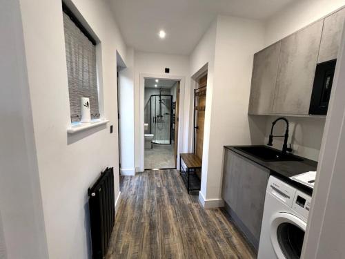 a kitchen with a sink and a washer and dryer at Modern Studio Apartment Near Glenfield Hospital in Glenfield
