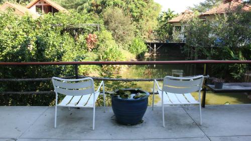 two chairs and a potted plant on a porch at Navari Homestay in Rayong