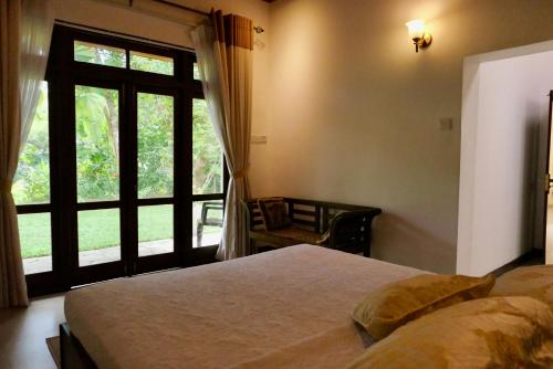 a bedroom with a bed and a large window at The Bliss Hostel Kandy in Kandy