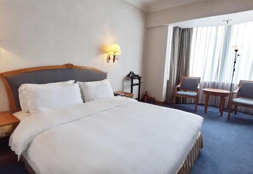 a hotel room with a large white bed and chairs at Rosedale Hotel & Suites Guangzhou - Free Shuttle Bus to Canton Fair in Guangzhou