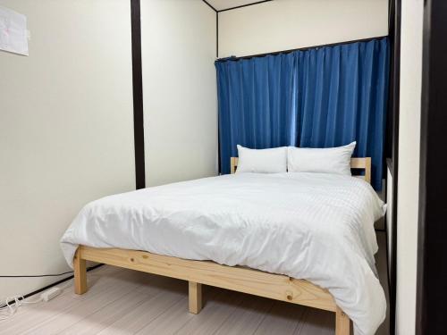 a bedroom with a bed with a blue curtain at A&C House 新大阪 in Osaka