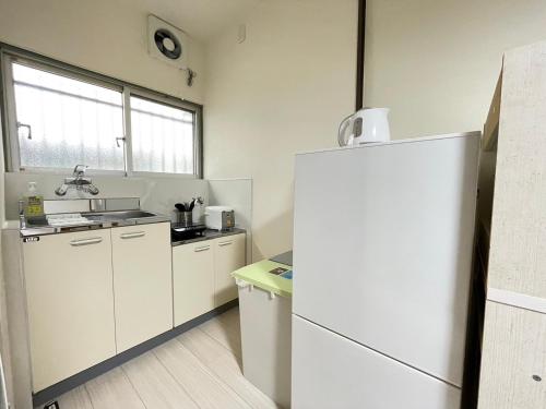 a kitchen with a white refrigerator and a sink at A&C House 新大阪 in Osaka