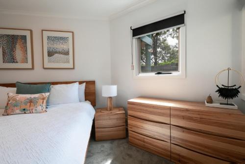 a bedroom with a bed with a wooden dresser and a window at The Dunes in Ocean Grove