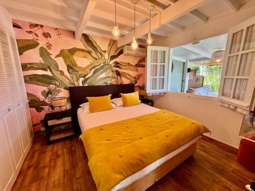 a bedroom with a large bed with a yellow blanket at Villa Pinky Créole vue mer proche plage in Trois Bassins