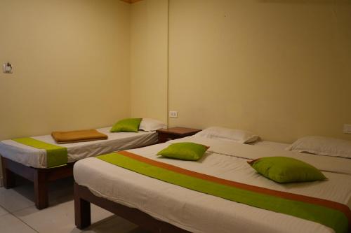 two beds in a room with green pillows on them at Coorg Inn in Kushālnagar