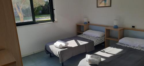 Cette chambre comprend 2 lits jumeaux et une fenêtre. dans l'établissement SERENA SWEET HOUSE, à SantʼAndrea Apostolo dello Ionio