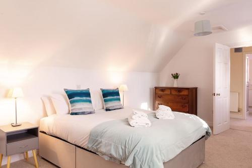 a bedroom with a large white bed with blue pillows at Chaveney Cottage in Quorndon