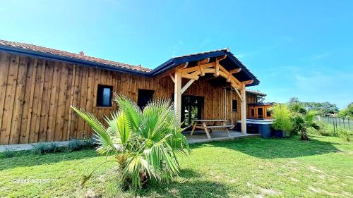 a wooden house with a picnic table in the yard at Les Bord'Océanes Sauna & Spa Villa Marensine et Villa Oyat in Vielle-Saint-Girons