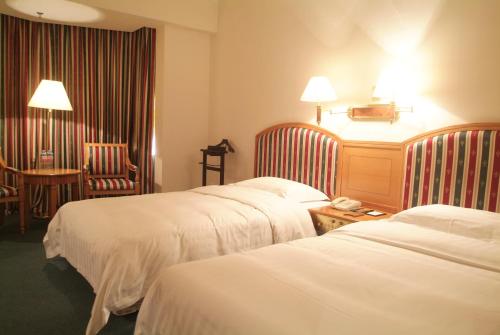 a hotel room with three beds and a table with a phone at Rosedale Hotel & Suites Guangzhou - Free Shuttle Bus to Canton Fair in Guangzhou