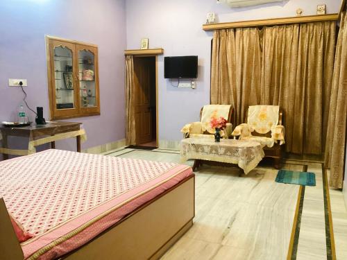 a bedroom with a bed and two chairs and a tv at Bikaner bliss - guest suite in Bikaner