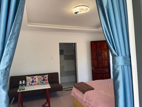 a bedroom with blue curtains and a bed and a couch at Bãi Xếp Beach in Quy Nhon