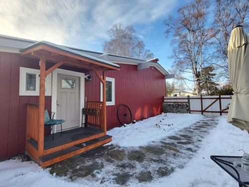 une maison rouge avec un kiosque dans la neige dans l'établissement A city studio, with a cabin-feel, for 1, à Fairbanks