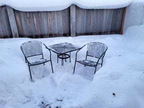 2 chaises et une table recouverte de neige dans l'établissement A city studio, with a cabin-feel, for 1, à Fairbanks