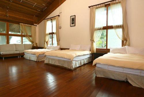 光復鄉的住宿－盛夏的軌跡，配有木地板和窗户的客房内的三张床