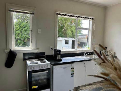 a kitchen with a stove and two windows at Oamaru Villa in Oamaru