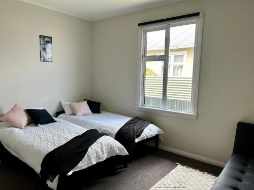 two beds in a room with a window at Oamaru Villa in Oamaru