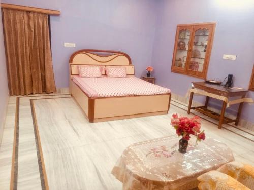 a bedroom with a bed and a table with a vase of flowers at Bikaner bliss - guest suite in Bikaner