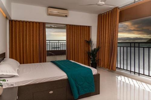een slaapkamer met een bed en een balkon met uitzicht bij Best sea view serviced apartments at marine drive cochin in Cochin