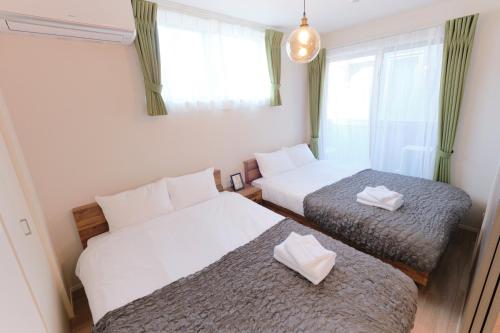 a small room with two beds and a window at EveryNet ShinjukuⅡ in Tokyo
