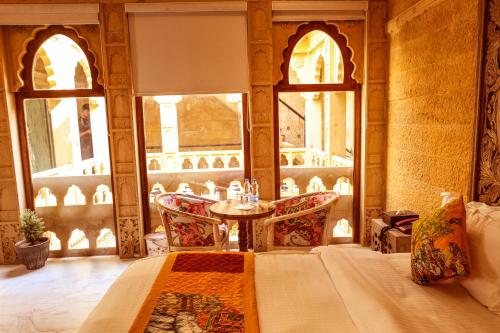 a bedroom with a bed and a table and chairs at Garh Meera - A Sensational Boutique Hotel in Jaisalmer