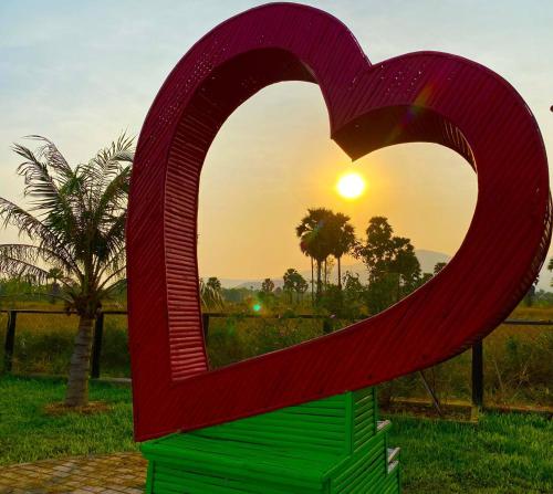 una gran escultura de corazón rojo frente a una puesta de sol en Ganesha Kampot Resort en Kampot