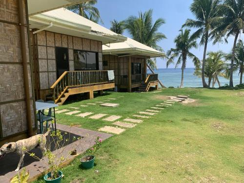 a house with a porch and the ocean in the background at Villa Malinao Oceanview Resort- Superior Bungalow in Burgos