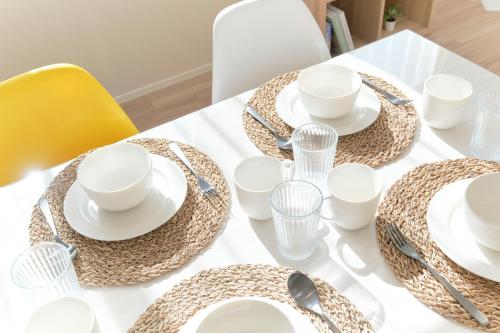 a table with white plates and cups and spoons at EveryNet ShinjukuⅡ in Tokyo