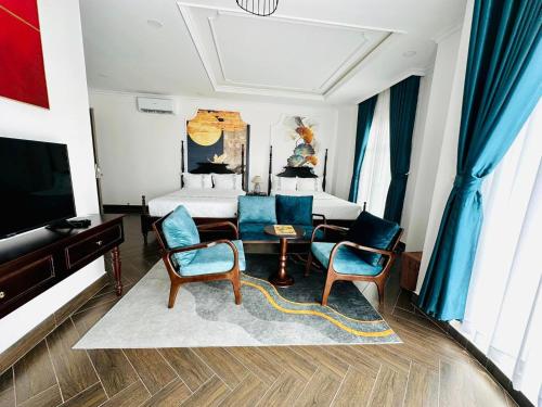 a bedroom with a bed and two chairs and a tv at Khách Sạn The One Hotel 1 in Cà Mau