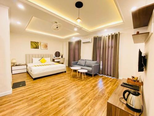 a bedroom with a bed and a couch and a table at Khách Sạn The One Hotel 1 in Cà Mau