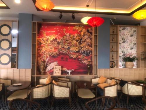 a restaurant with a large painting on the wall at Khách Sạn The One Hotel 1 in Cà Mau