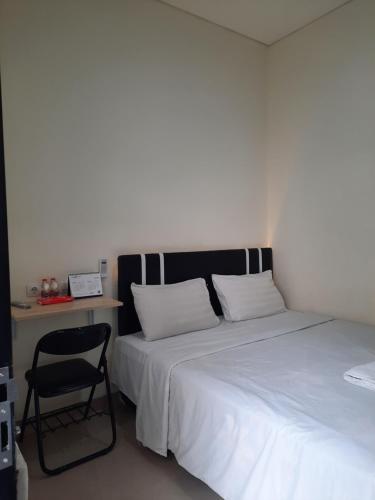 a bedroom with two beds with a chair and a desk at TRAM - The Seturan Raya Eksklusif Rooms in Seturan