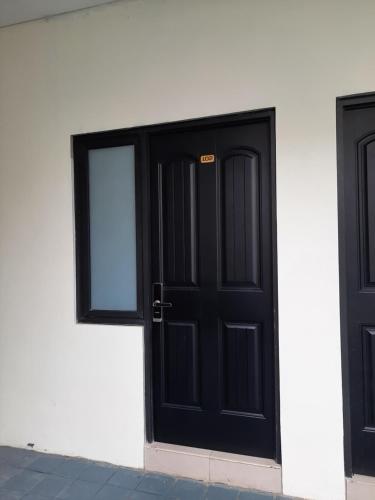 a black door on the side of a white building at TRAM - The Seturan Raya Eksklusif Rooms in Seturan
