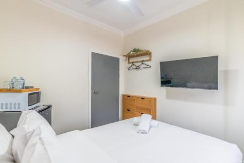 a white bedroom with a bed and a microwave at K2 Brisbane in Brisbane