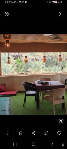 a table and two chairs in front of a window at Sehma Guest House بيت السحمه للضيافه in Al Ḩamrāʼ