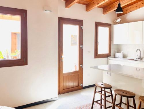 - une cuisine avec deux tabourets de bar et une porte en bois dans l'établissement Splendida Casa - 50 metri dal mare, à Portoscuso