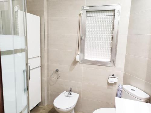 a bathroom with a toilet and a sink and a window at Acogedor y competo apartamento. in Villajoyosa