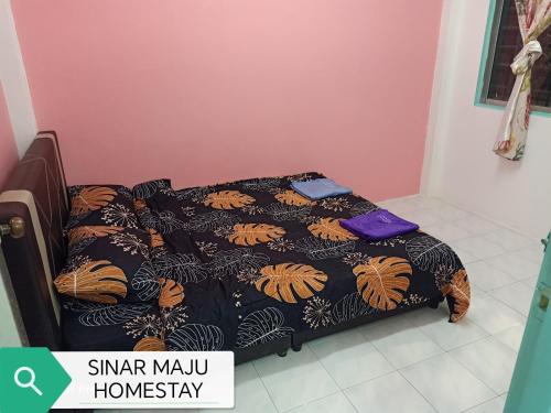 a bed in a room with a black and orange blanket at Sinar Maju Homestay in Tanah Rata