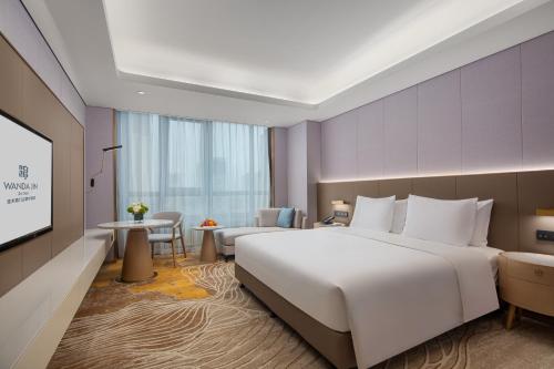 um quarto de hotel com uma cama grande e uma televisão em Wanda Jin Jiamusi em Jiamusi