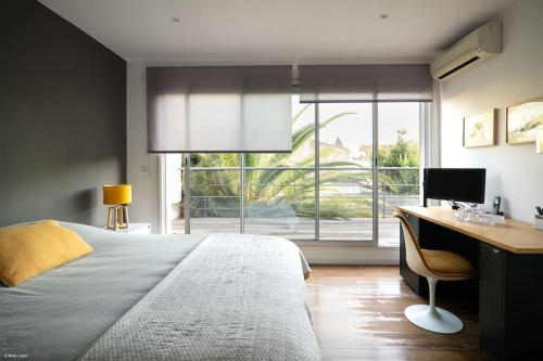 1 dormitorio con cama, escritorio y ventana en Superbe maison d'architecte entièrement climatisée avec piscine et spa professionnel, en Talence