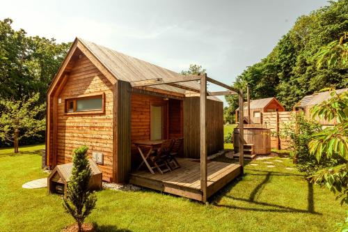 a small wooden cabin with a deck in a yard at Glamping Mountain Fairy Tale in Bistrica pri Tržiču