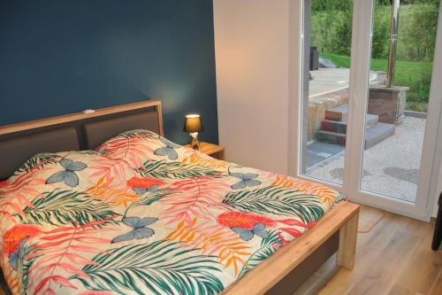 uma cama com um edredão colorido num quarto em Gîte la p'tite rivière em Saint-Nabord