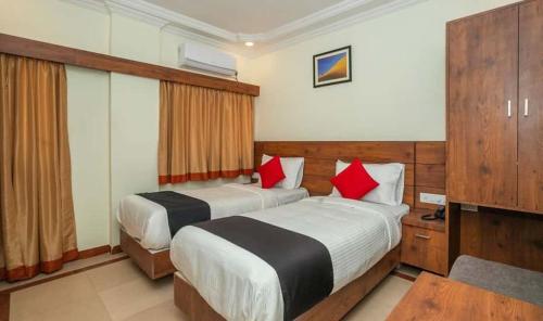 a hotel room with two beds with red pillows at HOTEL SAVI iNN in Bangalore