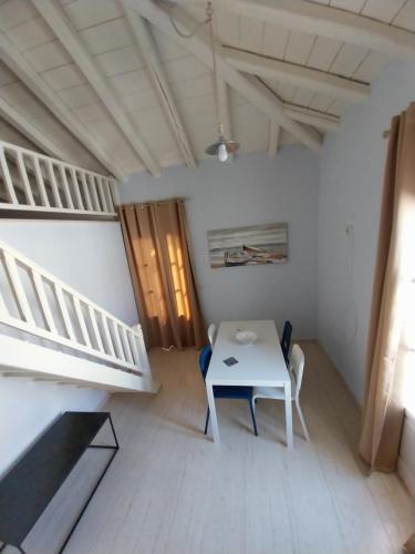 een witte kamer met een tafel en een trap bij Vivi's Apartments Loft in Spetses