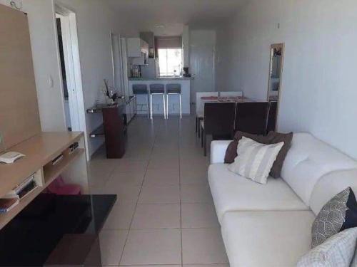 a living room with a white couch and a kitchen at Apart Canoa Quebrada vista mar- condominio fechado in Aracati