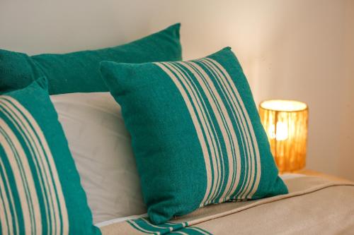 a bed with green and white pillows and a lamp at Hanah Apartments by Living Essaouira in Essaouira