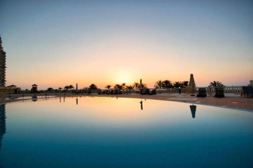 a large pool of water with the sunset in the background at Stunning high floor Ocean front Retreat with Panoramic Sea Views in Ras al Khaimah
