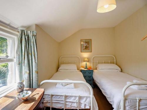 two beds in a room with a table and a window at 1 Penygroes in Penmachno